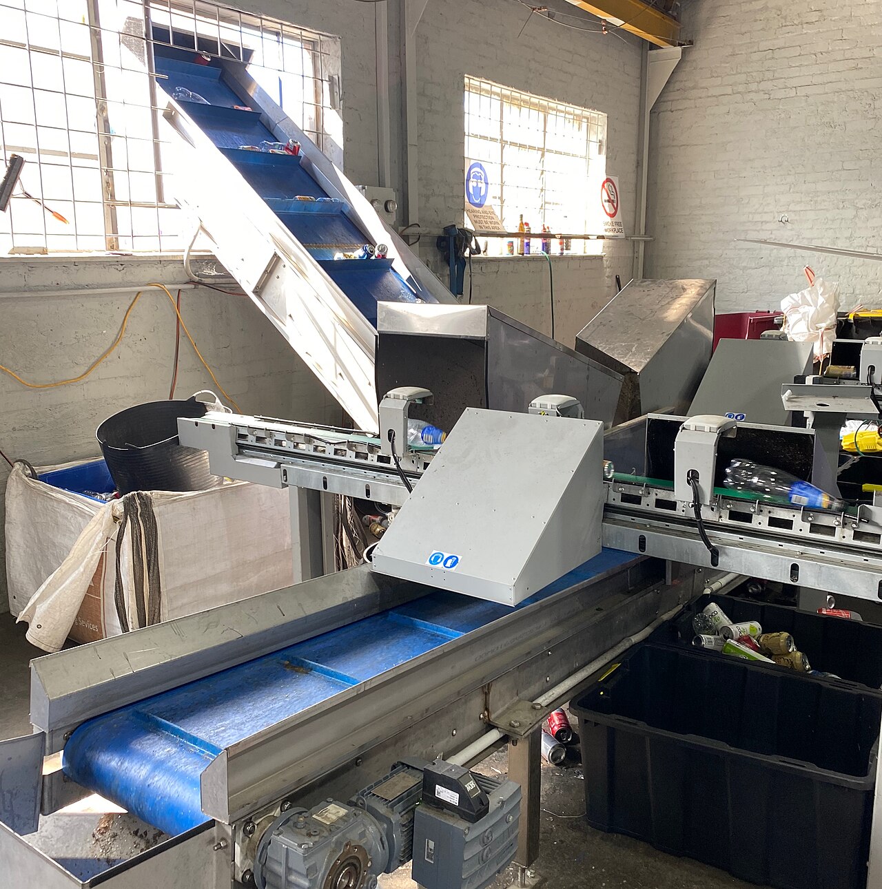 Automated conveyor belts and sensors sorting plastic bottles and aluminum cans inside a recycling facility.