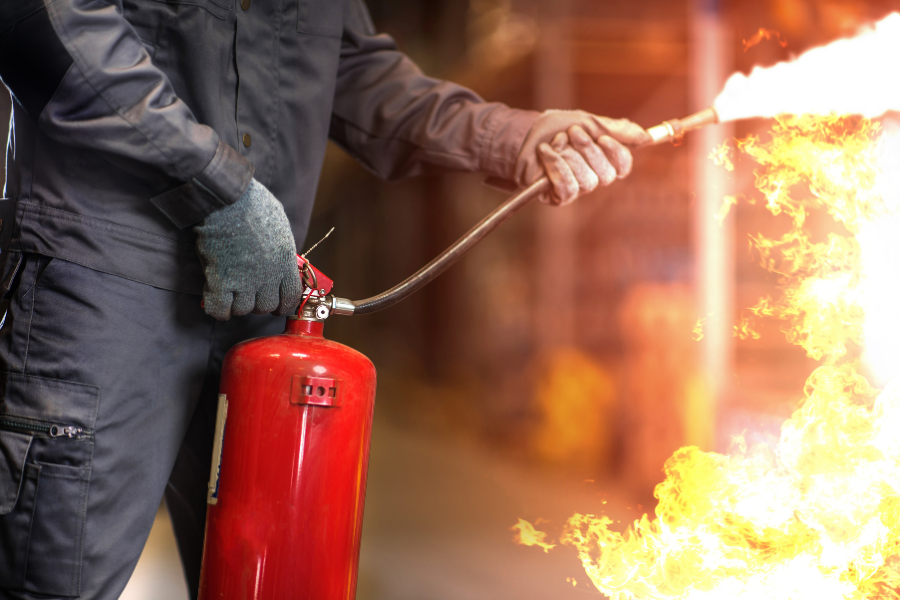 Worker using a fire extinguisher on a fire in an industrial facility