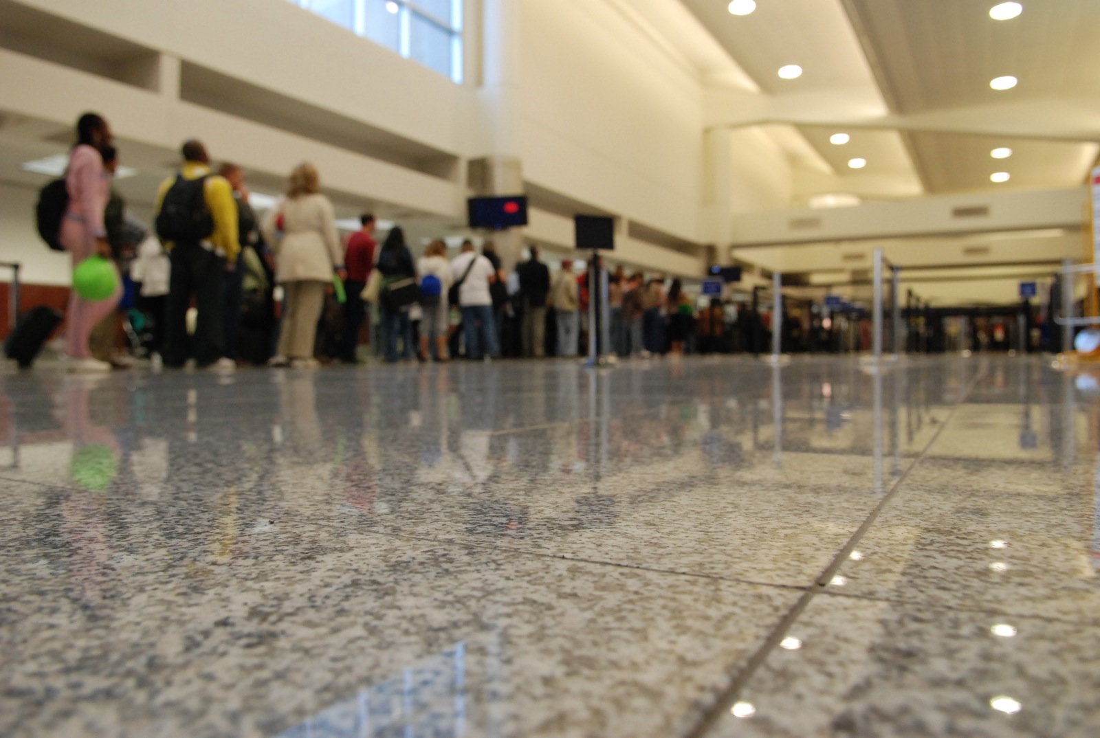 Travelers wait in a crowded airport security line in Atlanta, moving between black stanchions with carry-on bags and checkpoint tables visible ahead.